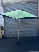 Full view of green patio umbrella on base