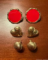 Front view of all three earring pairs laid out: red enamel round, hammered hearts, ribbed domes
