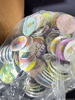 Bag of assorted coloured novelty buttons showing fronts and edges