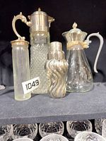 Group shot of four large vessels: diamond-pattern pitcher, glass carafe, ribbed cocktail shaker and slim bottle