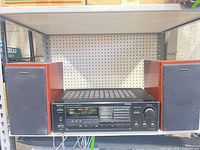 Receiver flanked by two speakers on shelf