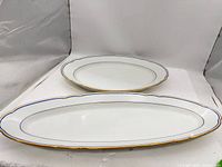 Two porcelain oval platters stacked, showing overall form and trim