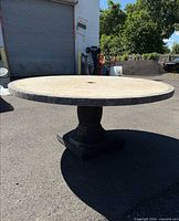 Full view of round patio table showing top, pedestal base, and umbrella hole