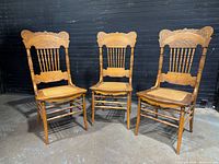 Front view of three matching oak Eastlake dining chairs showing overall design and condition