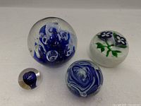 Four glass paperweights arranged together showing designs