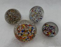 Front view of four glass paperweights showing designs and engraved piece