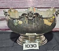Frontal view of silver plated punch bowl showing scalloped rim, mask cartouche, pedestal base