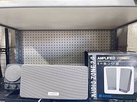 Sonos wireless speaker front, Boston satellite speaker with controls, Kinyo Audio Zone 2.0 boxed pair on shelf