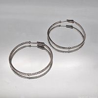 Both sterling silver hoop earrings laid flat to show overall design and condition