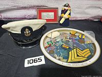 Group shot of cap, tray, medals, patches, dog tags, framed print, figurine