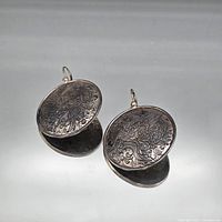 front view showing both round oxidized silver-tone earrings with dragon engraving and hooks