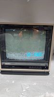 Front view of Quasar Dynacolor portable CRT TV powered on displaying static
