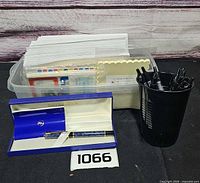 Lot overview showing Waterman pen in box, cup of pens and bin of stationery