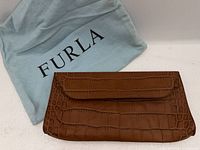 Front view of brown croc-embossed Furla clutch beside dust bag