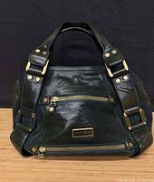 Front view of dark green Jimmy Choo leather handbag showing gold-tone hardware and front zip pocket