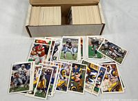 Open two-row cardboard box filled with white-border 1994 Fleer football cards; loose sample cards spread in foreground