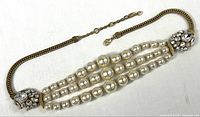 Full view of triple-strand pearl necklace with crystal endcaps and adjustable chain