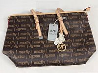 Front view of MaxFly monogram tote showing logo pattern, handles with protective wrap, hang tag, MF charm