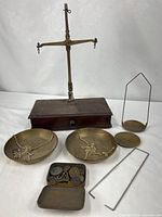 Overall view of balance scale, pans, extra hangers, tin and weights