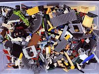 Top view of bin showing mixed LEGO bricks, plates, wheels, minifigure parts