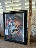 Full view of framed Archer: Dreamland signed poster with measuring stick indicating height
