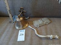 Overview of brass bell, anchor mount, rope pull, and glass car figurine on sofa
