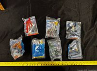 Seven sealed Burger King Fantastic Four toys arranged with measuring tape for scale