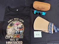 All items laid out: T-shirt, sunglasses, visor, case, small card