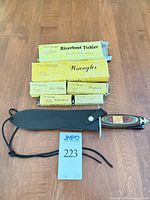 Dagger with sheath and six boxed folding knives on table