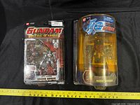 Front view of both sealed Bandai G Gundam action figures: Shadow Gundam on blister card and Haow Gundam in clamshell, ruler for scale