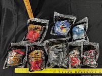 Front view of eight sealed McDonald’s The Incredibles Happy Meal toys with rulers for scale
