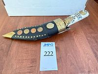 Kukri in sheath, showing bone handle, brass mounts and coin decorations