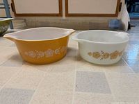 Both Pyrex Butterfly Gold casserole dishes side by side