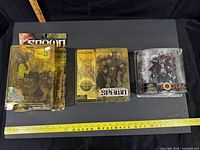 Front view of three blister-packaged Spawn series figures aligned on board with rulers for scale