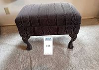 Full view of piano bench showing upholstery and carved claw feet
