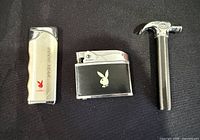 Front view of three lighters showing Playboy 2000 Year, Playboy black flip-top, and hammer-shaped lighter