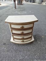 Front view of cream and gold wooden jewelry chest showing four drawers closed