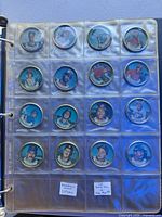Binder sheet with sixteen metal baseball coins displayed