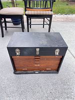 Front view of closed black toolbox with latches and wood drawer fronts