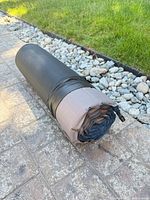 Rolled sleeping pad with black sleeve on patio