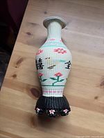 Full view front of woven plastic vase showing floral and bird design