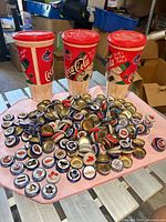 Full lot view: three Coca-Cola cups behind pile of NHL bottle caps