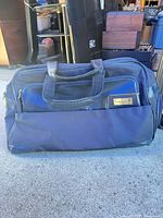 Full view of navy blue Johnnie Walker duffel bag showing size, color and front pocket