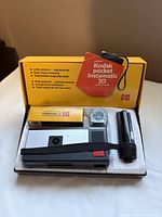 Open Kodak box showing camera, flashcube, film box, strap and accessory in foam insert