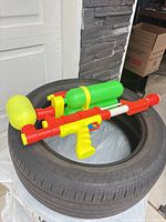 Full view of Larami water blaster showing red/yellow body and green reservoirs