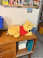 Full view of Winnie the Pooh plush on cabinet