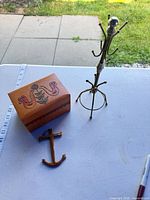 Group shot showing jewelry box, metal stand, anchor pendant with ruler for scale