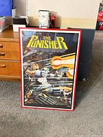 Full view of framed Punisher poster leaning against furniture