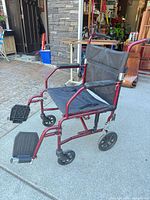 Side view of red Medline transport wheelchair showing frame, wheels, footrests