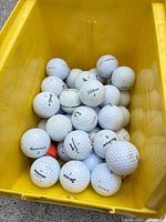 Top view of yellow bin filled with mixed golf balls